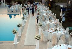 an outdoor wedding setup with tables and chairs set up by the pool for guests to enjoy