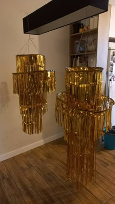 two gold chandeliers hanging from the ceiling in a room with wooden floors and walls