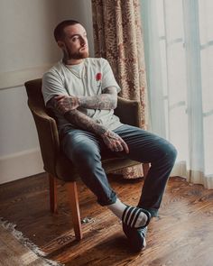 a man with tattoos sitting in a chair