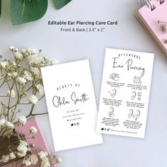 two white cards with black ink on them sitting next to flowers and other items that include pens