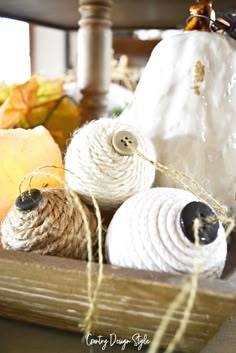 yarn balls and pumpkins in a basket on a table with other fall decor items