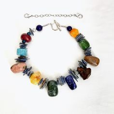 A rich combination of shapes, colors, and textures.  The necklace displays the beauty of different natural stones.  A simple organic beaded necklace with Agate, Kyanite, Wood, Sodalite, Rhodonite, Unakite, Boxwood Lotus Pod, and Dragon Bloodstones. Multicolor Lapis Lazuli Beaded Necklaces With Natural Stones, Multicolor Lapis Lazuli Natural Stones Beaded Necklace, Multicolor Lapis Lazuli Beaded Necklace With Natural Stones, Multicolor Beaded Necklaces With Lapis Lazuli Stones, Multicolor Lapis Lazuli Gemstone Beaded Necklaces, Multicolor Multi-stone Beads And Cabochons For Jewelry Making, Multicolor Multi-stone Beads For Jewelry Making, Multicolor Lapis Lazuli Necklaces With Natural Stones, Earthy Multicolor Gemstone Beaded Necklaces