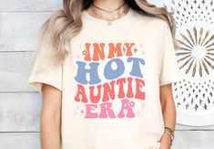 Step into the 'Aunti Era' with this retro-cool shirt, perfect for the hot auntie in your life. A fun pregnancy reveal or baby shower gift that's both trendy and nostalgic! * Q U I C K * F A C T S * ✺ 100% preshrunk cotton ✺ Wash and dry normally (on cool for best results) * S I Z I N G * ✺ Sizing is unisex so runs like men's, though not overly large ✺ Most women find their typical size works best, since they are meant to fit a touch loose* ✺ Size guide and fit: small - 2XL * S H I P P I N G * T Retro Cotton Tops For Mother's Day, Retro Letter Print Tops For Gifts, Retro Letter Print Tops As Gift, Retro Cotton Shirt With Funny Text, Mother's Day Vintage Short Sleeve Tops, Vintage Short Sleeve Tops For Mother's Day, Retro Tops With Funny Print As Gift, Vintage Screen Print Tops For Gift, Vintage Screen Print Tops As Gift