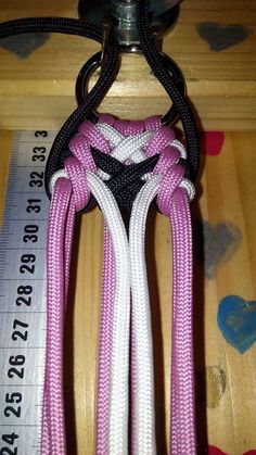 a pair of pink and white ropes attached to a hook on a wooden table with measuring tape