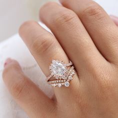 a woman's hand with a diamond ring on top of her wedding band and an engagement ring in the middle