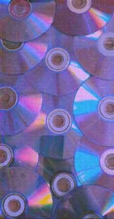 many cd's are stacked on top of each other with different colored discs in the middle