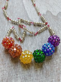 Fun rainbow style necklace with Cluster Faceted multi color acrylic beads. Accented with small glass beads on hot pink metal wire. Lobster clasp. Adjustable Rainbow Crystal Necklace With Faceted Beads, Adjustable Rainbow Faceted Beads Necklace, Rainbow Faceted Round Bead Necklaces, Rainbow Necklaces With Spacer Beads For Jewelry Making, Adjustable Rainbow Necklace With Colorful Beads, Rainbow Round Bead Adjustable Necklace, Rainbow Colorful Beads Necklaces For Jewelry Making, Adjustable Rainbow Round Bead Necklaces, Rainbow Colorful Beaded Necklaces For Jewelry Making