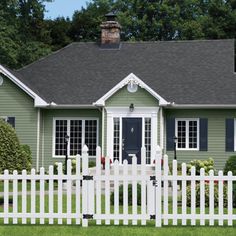 a green house with white picket fence