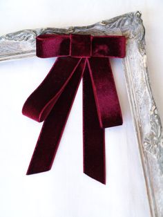 a red bow is hanging from a silver frame