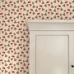 a white cabinet sitting in front of a wallpapered wall