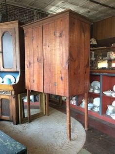 an old wooden cabinet is in the middle of a room filled with other antique items