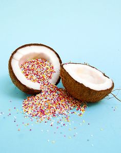 two coconuts with sprinkles and one cut in half on a blue background