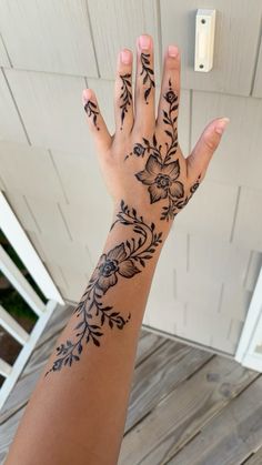 a woman's hand with tattoos on it and flowers in the middle of her arm