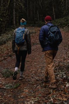 two people with backpacks walking in the woods