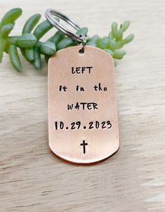 a copper dog tag that says, let it in the water 10 29 2013 with a cross