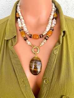 Mother of Pearl, Agate and Cat's Eye Double Strand Necklace with Tiger's Eye Pendant This elegant necklace set is a great gift for yourself and your loved ones. Made from genuine gemstone beads. All metal ornaments are 18K gold plated and won't get darker in time! This collection comprises two exquisite necklaces that offer the versatility of being worn individually or elegantly layered together. (Longer one is 19 inches and shorter one is 16.5 inches ) FREE SHIPPING ✈️✈️ - All orders get shippe Earth Tone Jewelry, Metal Ornaments, Jewerly Beads, Double Strand Necklace, Dangle Necklaces, Cats Eye, Eye Pendant, Statement Necklaces, Tigers Eye