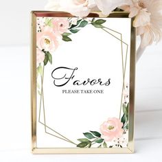 a white and pink flower arrangement in a gold frame with the words favors please take one