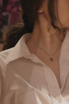 a woman wearing a white shirt with a necklace on her neck