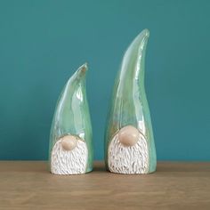 two ceramic figurines sitting on top of a wooden table