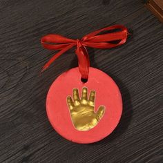 an ornament with a handprint on it and a red ribbon around the edge