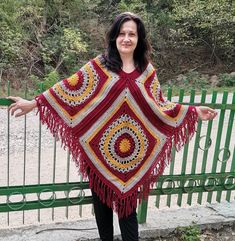 a woman standing in front of a fence wearing a crocheted shawl