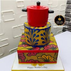 a colorful cake with a red fondant pot on top