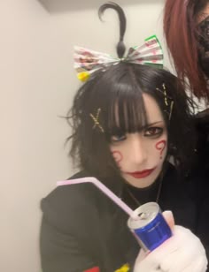 two women dressed up in costumes with makeup on their faces and one holding a drink