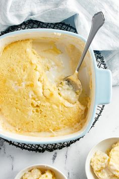 two bowls filled with mashed potatoes on top of a white marble counter next to silverware