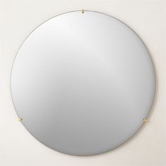 a round mirror with gold studs on the edges and a white wall behind it