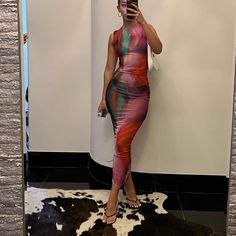 a woman taking a selfie in front of a mirror wearing a colorful dress and holding a cell phone