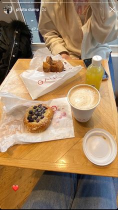 two people are sitting at a table with pastries and drinks on it in front of them