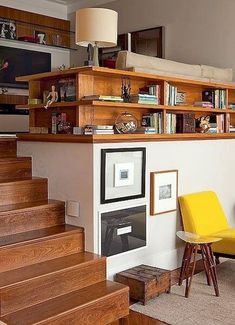 a living room filled with furniture and bookshelves next to a stair case full of books