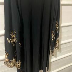 Msk Black Dress Above The Knee With Sequence And Embroidery On The Arms Fitted Embroidered Black Abaya, Fitted Black Abaya For Eid, Black Long Sleeve Abaya With Floral Embroidery, Elegant Embroidered Black Abaya, Elegant Black Abaya With Floral Embroidery, Black Embroidered Abaya For Wedding, Black Embroidered Wedding Abaya, Wedding Black Embroidered Abaya, Embroidered Long Sleeve Abaya For Party