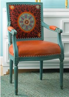 an orange and blue chair in front of a wall with a clock painted on it