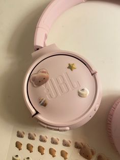 a pair of pink headphones sitting on top of a white table next to some stickers