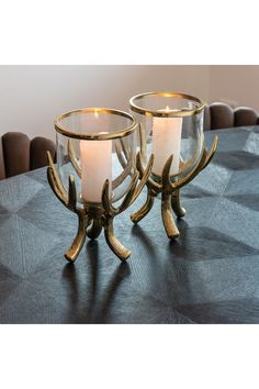 two candles sitting on top of a table next to each other with antler legs