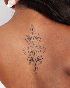 the back of a woman's neck with an intricate tattoo design on her left shoulder