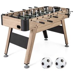 a foosball table with two soccer balls in front of it and an extra foosball next to it