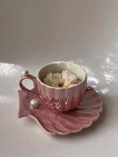 a pink tea cup and saucer with flowers in it