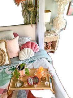 a bed with many pillows on top of it next to a tray filled with plants