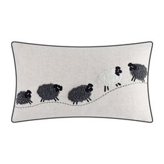 a white pillow with black sheep on the side and an embroidered line down the middle