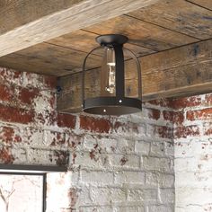 a light fixture hanging from the ceiling in a room with brick walls and wood beams