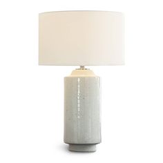 a table lamp with a white shade on the base and a light bulb attached to it