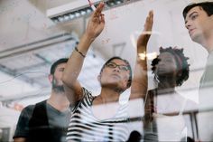 a group of people standing around each other in front of a glass wall with writing on it