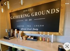 the sign for gathering grounds is displayed on the wall behind the coffee shop's counter