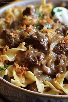 a bowl filled with pasta and meat covered in sauce