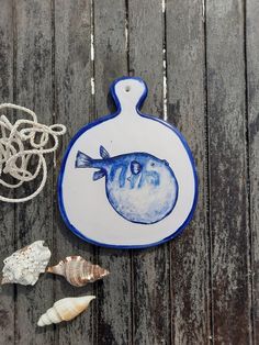 a blue and white plate sitting on top of a wooden table next to sea shells