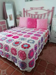 a bed with pink and white crocheted bedspread on top of it