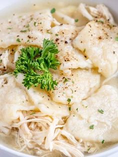 a white bowl filled with dumplings and garnished with parsley on top