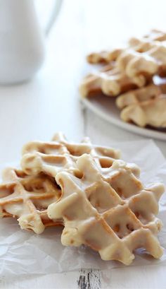 two waffles with icing sitting on top of each other next to a cup